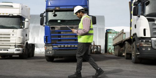 full-shot-man-walking-by-trucks-fleet